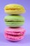 Trio french colorful cookies one on top of each other on purple background. Vertical pile of biscuits with different interlayers