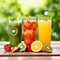 Trio of fresh healthy fruit juice blends in tall glasses on a summer picnic table outdoors with orange