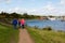 A trio of friends enjoying a walk along a river path next to the river Deben in Suffolk on a sunny day