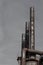 Trio of rusted and riveted metal smokestacks against a dark grey sky, copy space