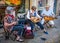 Trio of seated musicians playing Hurdy Gurdys in the street in Beaune, Burgundy, France