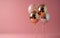 a trio of shiny balloons on a pink background,