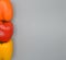 A Trio of Three Yellow Orange and Red Bell Peppers on a Gray Background