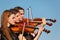 Trio of violinists plays against sky