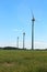 A trio wind turbines in the middle of a field
