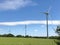 A trio wind turbines in the middle of a field landscape