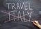 Trip to Italy. A woman`s hand crosses out the inscription Italy on a chalkboard. Cancellation of the tour due to the epidemic