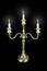 Triple bronze candelabrum with three burning candles on black background