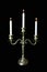 Triple bronze candelabrum with three long burning candles on black background