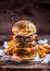 Triple cheeseburger with beef patty, melted cheese, egg and peppers in a rustic wooden environment