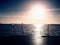 Tripod with camera ready on pier, Sun above ocean. Empty wooden mole board