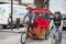 Trishaw and cyclist riding on the road