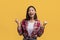 Triumphant asian lady shaking clenched fists and shouting in excitement on yellow studio background