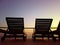 Tropical background with couple of deck chairs at sunset by sea. It is beautiful view of golden sun