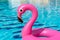 Tropical background. Pink inflatable flamingo in pool water for summer beach background. Minimal summer concept