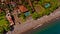 The tropical bay with stony beach, boats and buildings, aerial view.