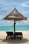 Tropical beach with deckchairs and umbrella over lagoon sea water