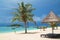 Tropical beach with deckchairs, umbrellas, boats and palm trees