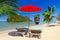 Tropical beach scenery with parasol and deck chairs