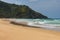 Tropical beach on sunny day with surfers. Duli surf beach in Palawan, Philippines. Wide beach with green mountain on background.