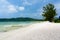 Tropical beach with turquoise clean water, blue sky, white sand and boat in the distance