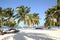 Tropical beach with white sand, palm trees and sailboats