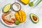tropical bowl with avocado, prawns, rice, mango, kiwi and coconut, tropical food on the sea beach on light background with