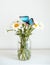 tropical butterfly Morpho sits on a white flower in a bouquet of large daisies and gerberas on a white background, macro