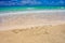 Tropical Caribbean beach in Bahamas with bright blue sky, turquoise water and writing on the sand