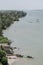 Tropical coast line with narrow gray beach, palms, lush vegetation and wooden fishing boats, Ndiebene, Senegal