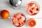 Tropical cocktail with ice cubes in glasses, fruit and shaker on wooden background