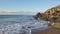 Tropical early morning sunrise on the beach with frothy waves, smooth sand and volcanic rocks