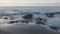 Tropical early morning sunrise on the beach with frothy waves, smooth sand and volcanic rocks