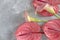 Tropical flowers pink anthuriums and calla lilies on a gray background. Flat lay, top view.