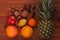 Tropical fruits and nuts vegan diet. Pineapple, grapefruit, orange, pear, walnuts on wooden background,weight loss foods