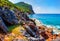 Tropical landscape of rocky coastline with mountains and blue sea water on clear sunny summer day