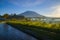 Tropical landscape during sunrise. Scenic view to Agung Volcano. River and rice fields in the village. Bali, Indonesia