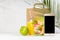 Tropical lunch set of orange juice, sea food shrimp salad in box, blank phone, packet in white restaurant interior, palm leaf.