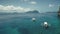 Tropical ocean aerial: boats, ships, yachts at blue water. Serene sea bay at island cliff shore