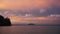 Tropical ocean view with far away island in pink sunset twilight sky