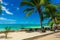 Tropical resort with chaise longs under palms on sandy beach