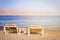 tropical sea beach and two chaise lounger at sunset light. Summer travel and vacation concept