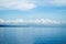 Tropical seascape with distant island and blue sky. Relaxing sea view with still seawater.