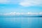 Tropical seascape with distant island and blue sky. Relaxing sea view with still seawater.