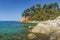 Tropical seascape on mediterranean shore with rocks and stones in transparent blue water on sunny summer day