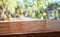 Tropical spring background.Empty diagonal brown wooden table with blur tree in park boekh background,banner mockup template for