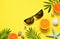 Tropical Summer Beach Background. Palm Trees Branches, tarfish, seashell, sunglasses and orange on yellow summer background.