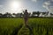 Tropical sunset bliss. Young beautiful and attractive Asian Chinese woman in elegant dress walking on green rice field enjoying