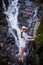 Tropical traveling. Young woman in hat enjoying waterfall view.