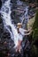 Tropical traveling. Young woman in hat enjoying waterfall view.